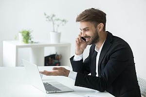 man sitting at his desk on the phone