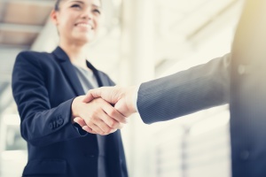 woman shaking hands after having sales management training